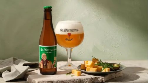 Glas en fles St.Bernardus Tripel, en een bordje met kaas. voor een lichte achtergrond