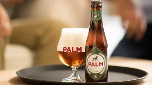 Palm glas en fles op een dienblad, proostende mensen vervaagd in de achtergrond