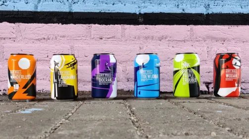Core range blikjes staan op een stoep, voor een roze/blauwe bakstenen achtergrond